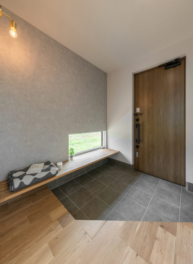 広めの土間に、ベンチにもなる飾り棚と地窓が素敵な玄関